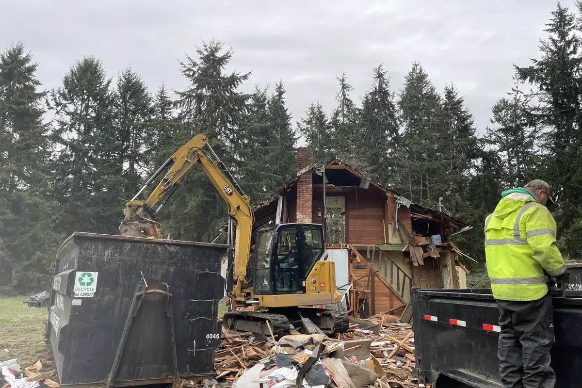 Excavator demolishing a structure and loading debris