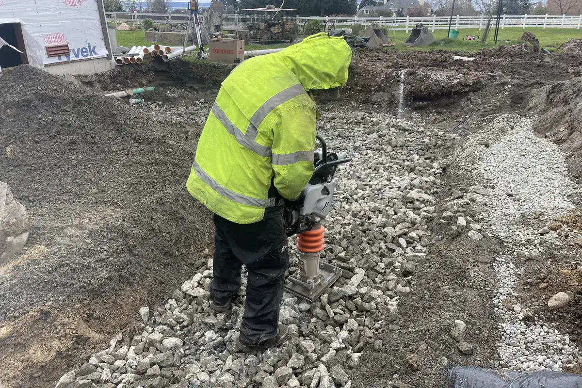 Crew setting drain rock over a new drainage line